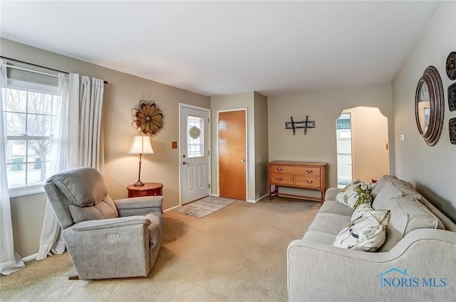 living area with light carpet and baseboards