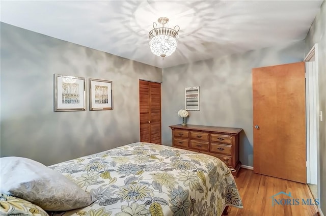 bedroom with an inviting chandelier, a closet, and wood finished floors