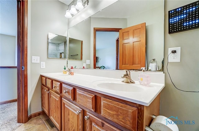 bathroom with double vanity, baseboards, a sink, and tile patterned floors