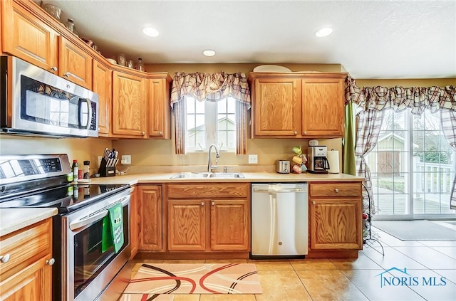 kitchen with light countertops, appliances with stainless steel finishes, a sink, and recessed lighting