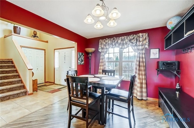 dining area featuring a chandelier, stairway, baseboards, and wood finished floors