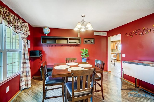 dining room with a chandelier, wood finished floors, visible vents, and baseboards