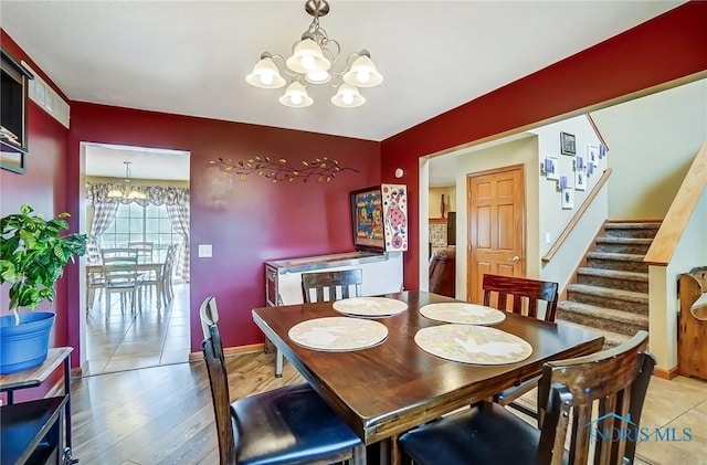 dining space featuring light wood-type flooring, stairway, baseboards, and a chandelier