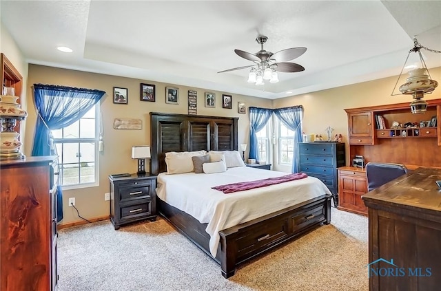 bedroom featuring a tray ceiling, a ceiling fan, light colored carpet, and baseboards