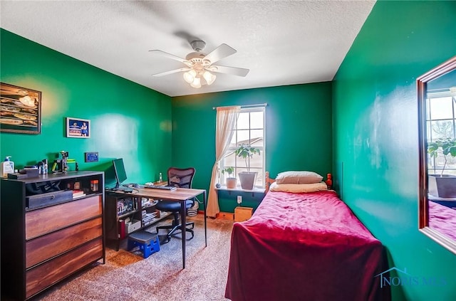 carpeted bedroom with ceiling fan and a textured ceiling