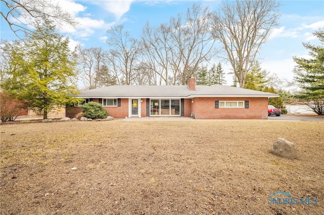 ranch-style home with a chimney and brick siding