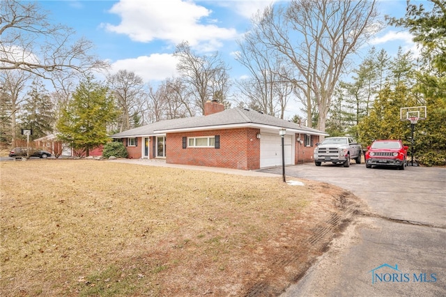 view of front of home featuring brick siding, a chimney, a garage, driveway, and a front lawn