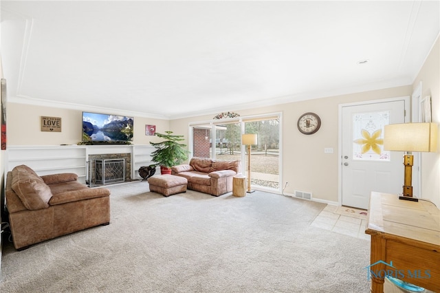 carpeted living area with baseboards, a fireplace with flush hearth, visible vents, and crown molding