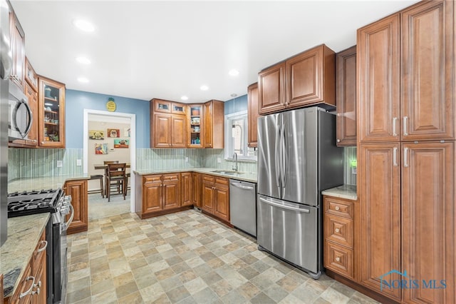 kitchen featuring brown cabinets, decorative backsplash, stainless steel appliances, and a sink