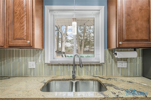 kitchen with light stone counters, decorative backsplash, and a sink