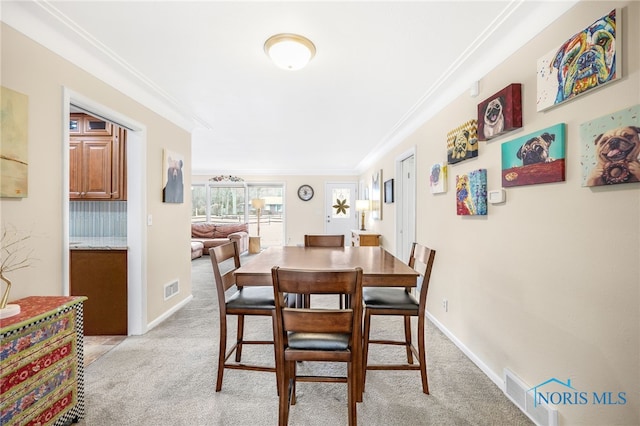 dining room with visible vents, ornamental molding, and light colored carpet