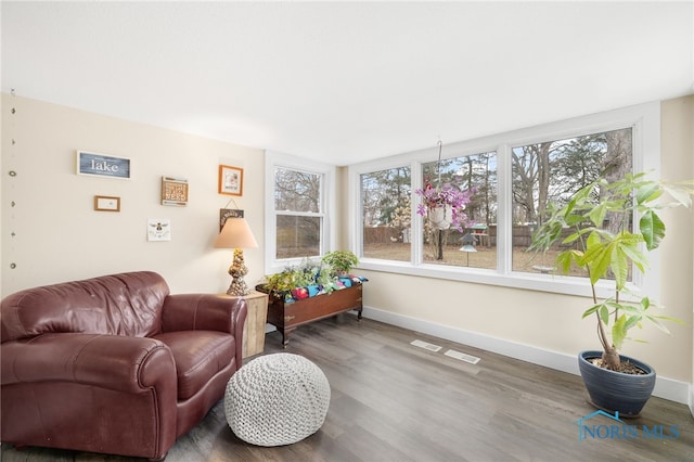 living area featuring a healthy amount of sunlight, visible vents, baseboards, and wood finished floors