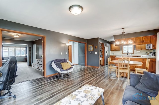 living area with baseboards, a notable chandelier, and light wood-style floors