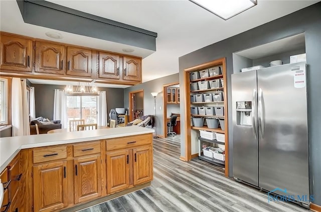 kitchen featuring light countertops, light wood-type flooring, stainless steel fridge, and brown cabinets