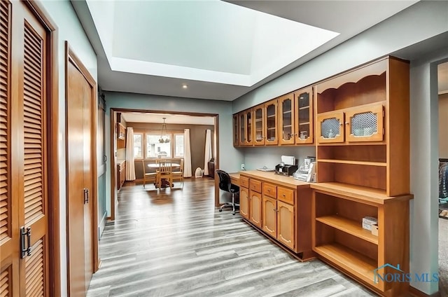 bar featuring light wood-style flooring, hanging light fixtures, and built in desk