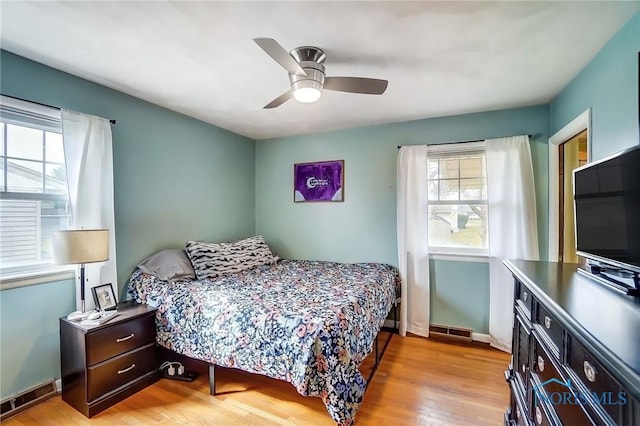 bedroom with light wood finished floors, baseboards, visible vents, and a ceiling fan