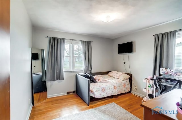 bedroom featuring baseboards, visible vents, and wood finished floors