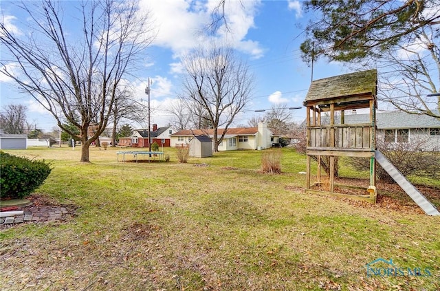 view of yard featuring a trampoline and an outbuilding