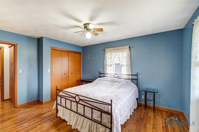 bedroom featuring a ceiling fan, a closet, baseboards, and wood finished floors