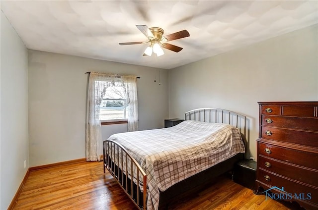 bedroom with a ceiling fan, baseboards, and wood finished floors