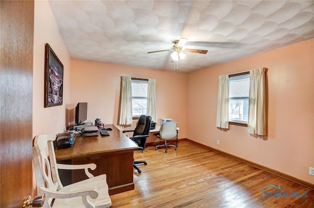 home office with a ceiling fan, baseboards, and wood finished floors