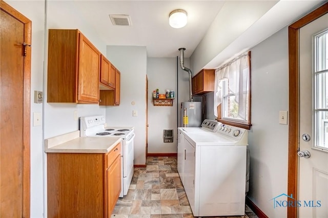 kitchen with electric range, visible vents, stone finish floor, light countertops, and water heater