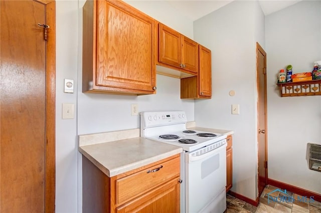 kitchen with brown cabinetry, white range with electric stovetop, light countertops, and baseboards