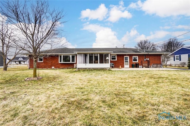 back of house featuring a yard, brick siding, and a sunroom