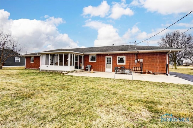 rear view of property with a sunroom, a patio, a lawn, and brick siding