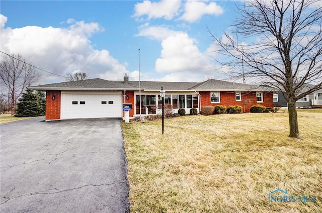 single story home featuring a front yard, brick siding, driveway, and an attached garage