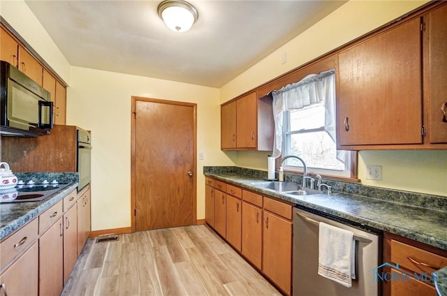 kitchen featuring wall oven, dishwasher, dark countertops, black microwave, and a sink