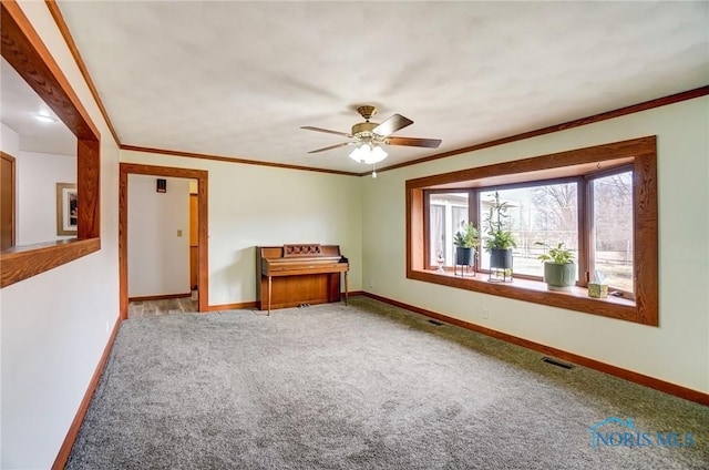 unfurnished room with baseboards, visible vents, a ceiling fan, ornamental molding, and carpet