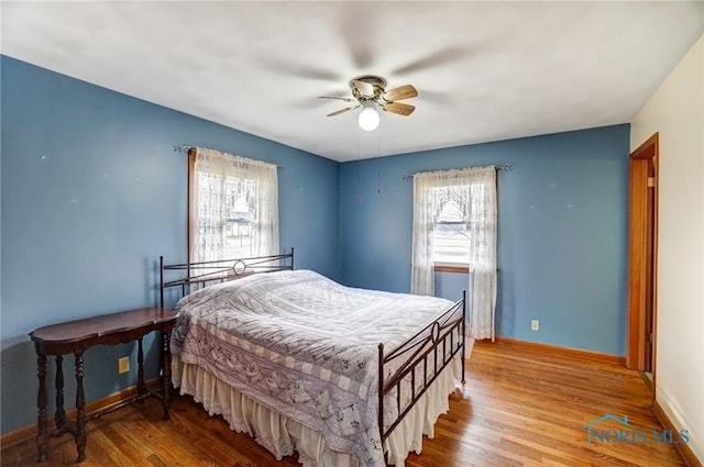 bedroom featuring a ceiling fan, baseboards, and wood finished floors