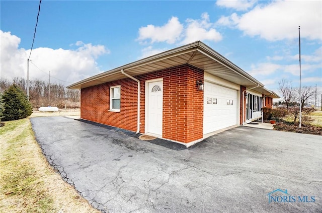 view of property exterior with driveway, brick siding, and an attached garage