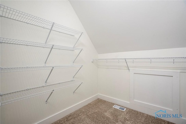 walk in closet with carpet, visible vents, and vaulted ceiling