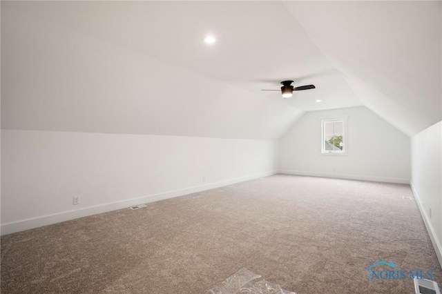 additional living space featuring visible vents, carpet flooring, vaulted ceiling, ceiling fan, and baseboards