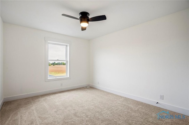 carpeted spare room with a ceiling fan and baseboards