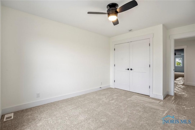 unfurnished bedroom featuring baseboards, visible vents, a ceiling fan, carpet, and a closet