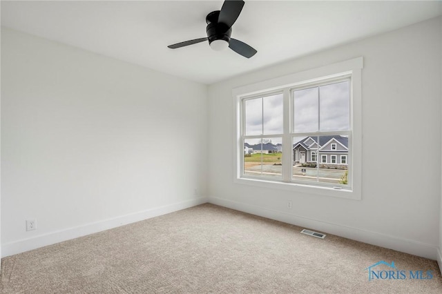 carpeted empty room featuring visible vents, ceiling fan, and baseboards