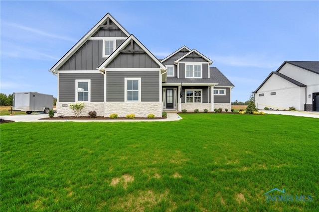 craftsman-style home with stone siding, a front lawn, and board and batten siding