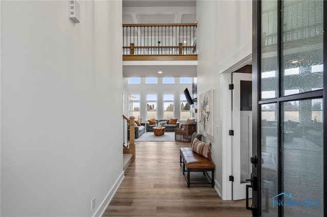 entrance foyer featuring a towering ceiling, stairs, baseboards, and wood finished floors