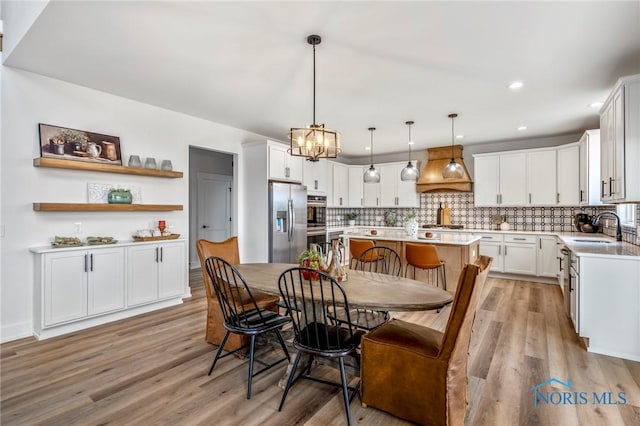 dining area featuring light wood-type flooring, recessed lighting, and an inviting chandelier