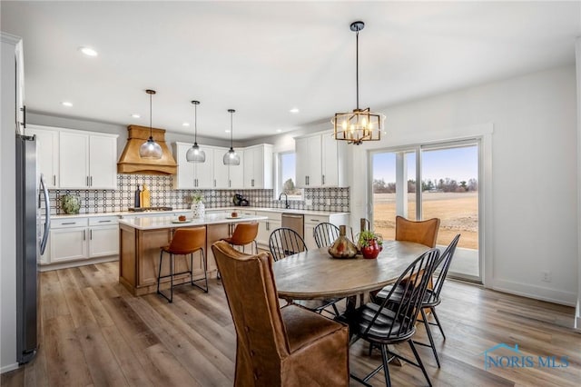 dining area featuring a notable chandelier, baseboards, wood finished floors, and recessed lighting