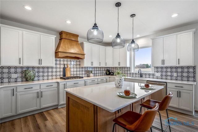 kitchen with a sink, premium range hood, stainless steel appliances, and light countertops