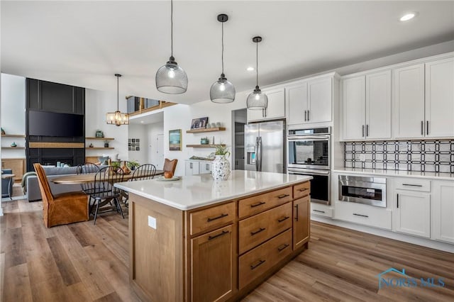 kitchen featuring stainless steel appliances, wood finished floors, open shelves, and light countertops