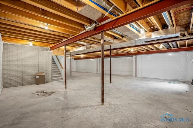 unfinished basement featuring brick wall and stairway