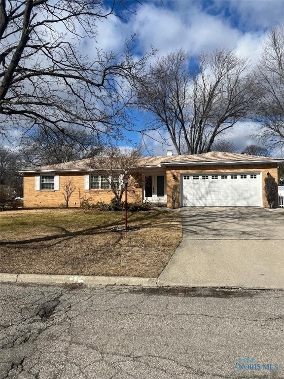 view of front of house with a garage, a front lawn, a chimney, and driveway