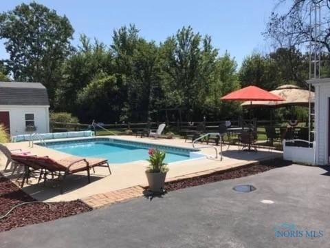 view of pool with a covered pool, a storage unit, an outbuilding, and a patio