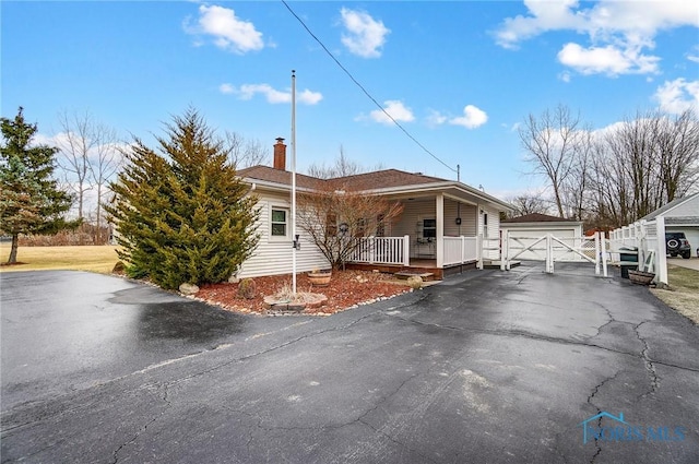 view of front of house with a garage, an outbuilding, covered porch, and a chimney