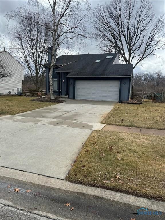 view of front of house with a garage, driveway, a chimney, and a front yard